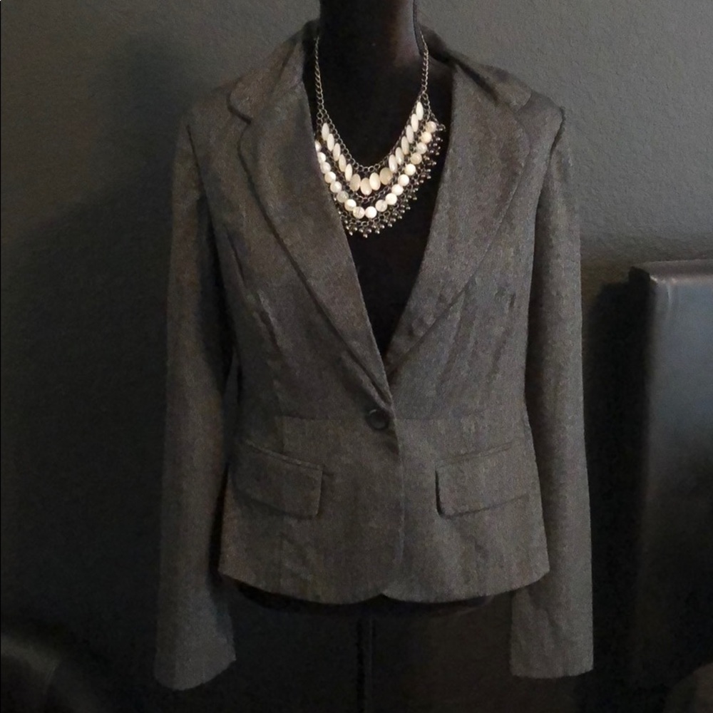 Gray women’s blazer with buttons in front.